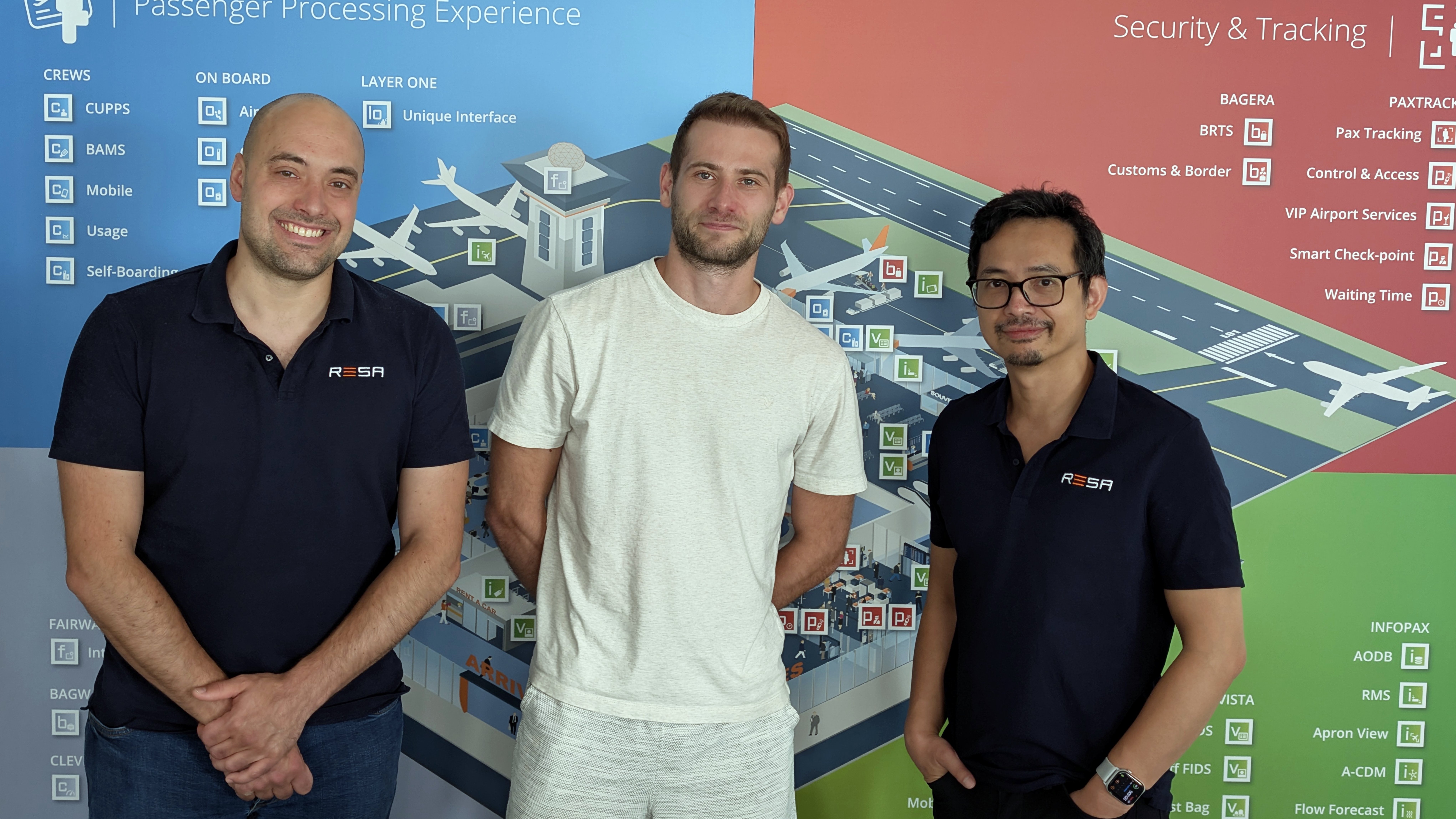 The Farel and RESA teams at RESA's office in front of the RESA CREWS and CUPPS product banner.