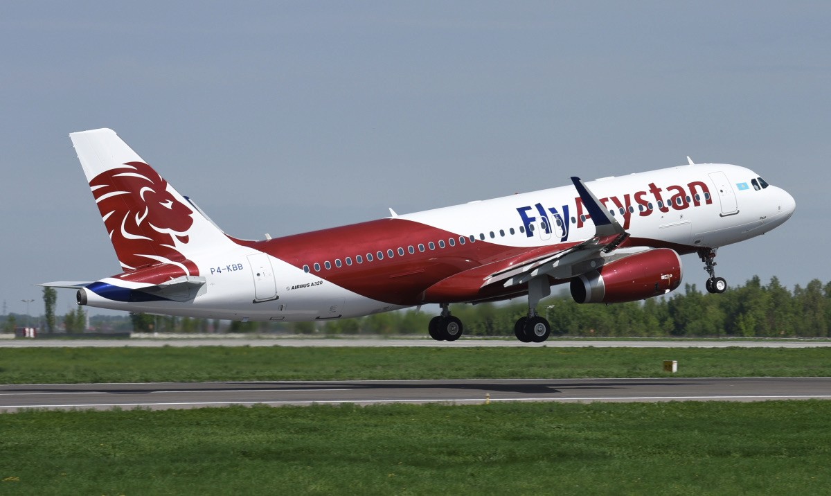 FlyArystan Airbus A320 in red and white livery taking off from a runway