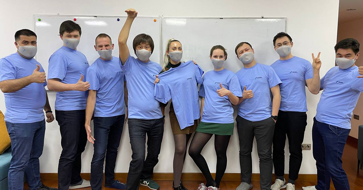 Farel team in matching blue T-shirts and face masks holding up branded merchandise